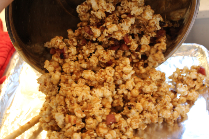 pouring the caramel corn onto a sheet pan